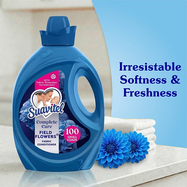 Suavitel Field Flowers blue bottle next to a stack of fluffy white towels and blue dahlia flowers. Text reads: Irresistible Softness and Freshness. 
