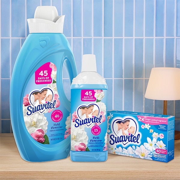 Suavitel Field Flowers fabric conditioner bottle, smaller bottle, and dryer sheets on a laundry table.